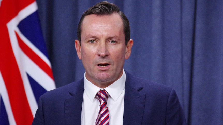 Head and shoulders pic of Mark McGowan with a flag in the background.