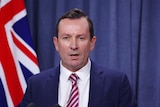 Head and shoulders pic of Mark McGowan with a flag in the background.