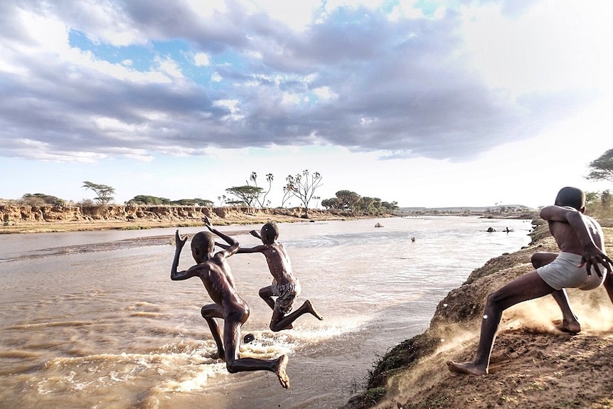 Three boys from Unity jump off the banks of the Ewaso Ng'iro River.