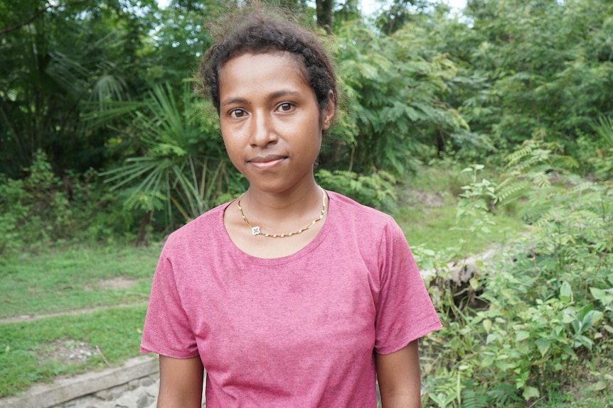 A young Timor-leste woman in a pink shirt in a rural setting. 