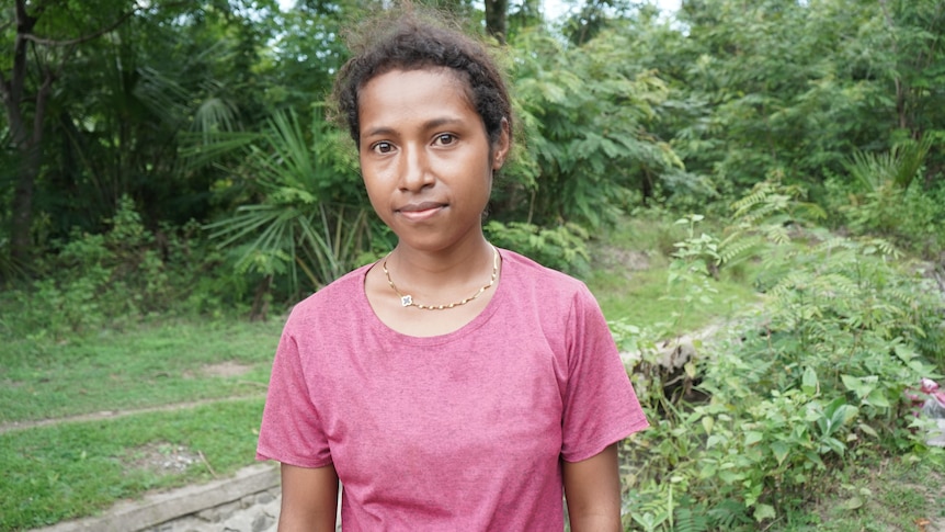 A young Timor-leste woman in a pink shirt in a rural setting. 