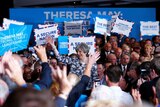 British Prime Minister Theresa May is surrounded by supporters holding up signs at a campaign event.