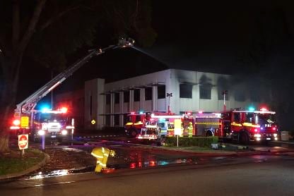 A wide shot of firefighters and fire trucks battling a factory fire on Pilbara Street in Welshpool at night.