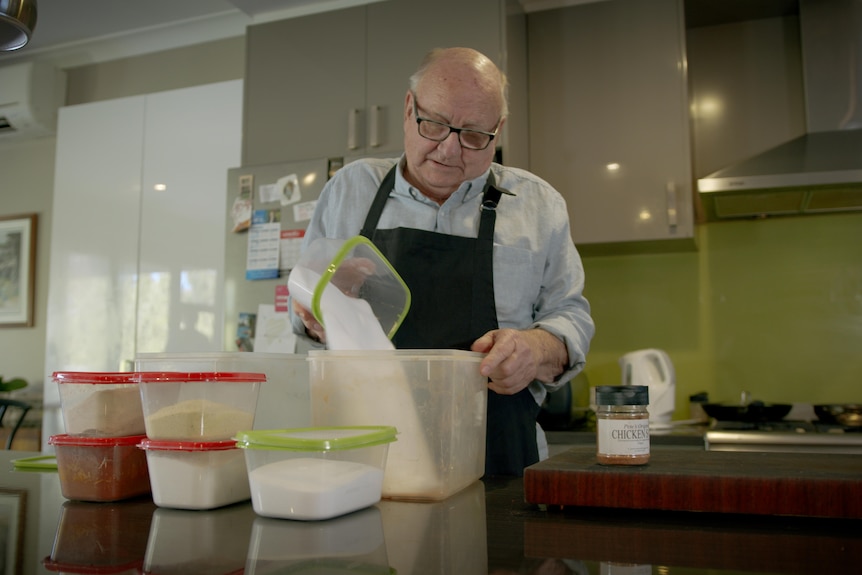 Bald old man with glasses pouring spices into container