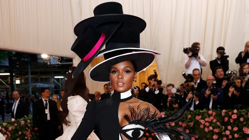 Janelle Monae wears a black, white and pink dress with four stacked top hats.