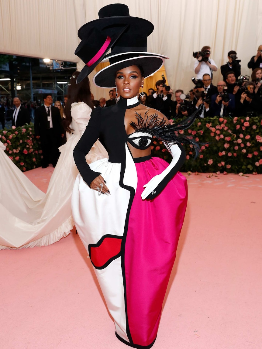 Janelle Monae wears a black, white and pink dress with four stacked top hats.
