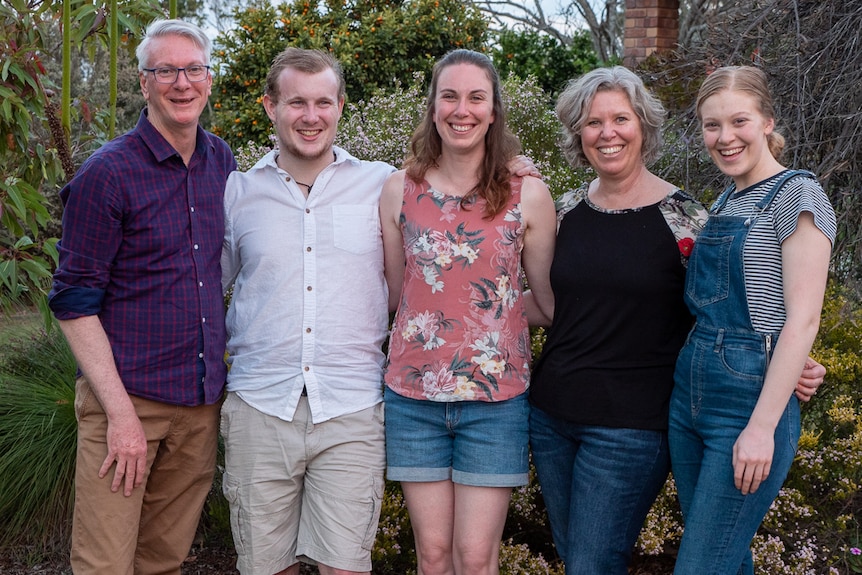 Two parents and three grown up children stand in their garden.