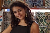 Woman dressed in a black dress stands in front of colourful tiles in a tile shop.