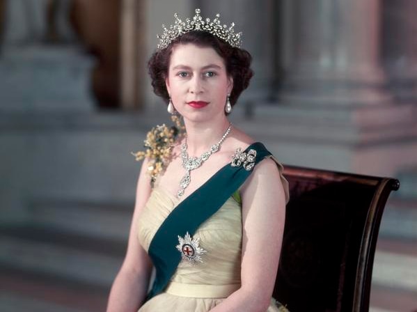 A young Queen Elizabeth wearing a sash and diamond tiara, necklace and broaches.