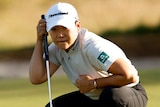 A South Korean female golfer crouches as reads the green ahead of putting at the Australian Open.