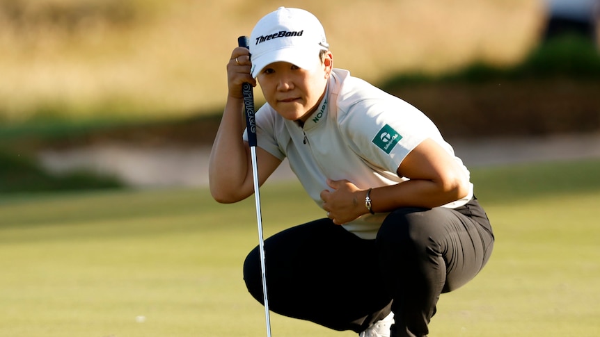 A South Korean female golfer crouches as reads the green ahead of putting at the Australian Open.