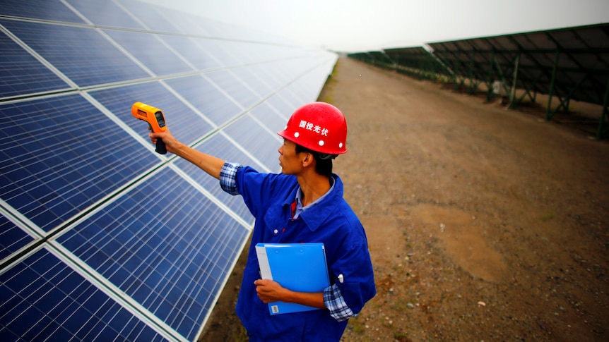 A worker inspects solar panels at a solar farm in China