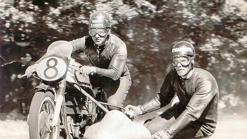 Two men on a 1950's motorbike and sidecar.  The photo is black and white