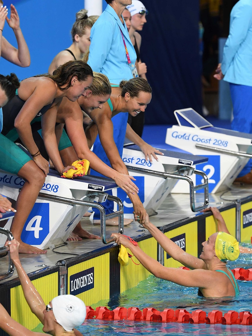 Ariarne Titmus is congratulated by her three relay teammates.