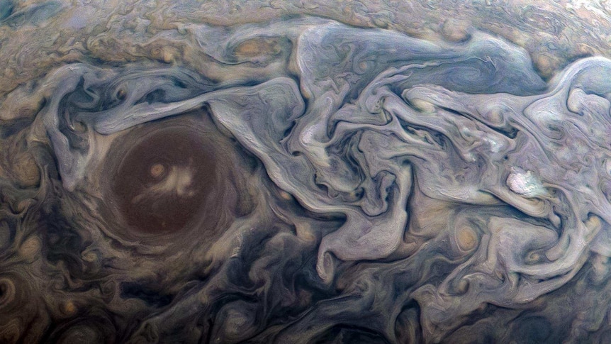 Purple, brown and bluish swirls whirls around each other with a fluid-like appearance