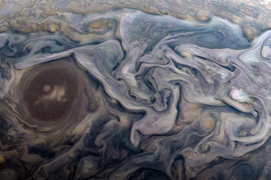 Purple, brown and bluish swirls whirls around each other with a fluid-like appearance