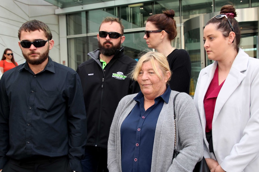 5 people stand grouped on the steps of court.