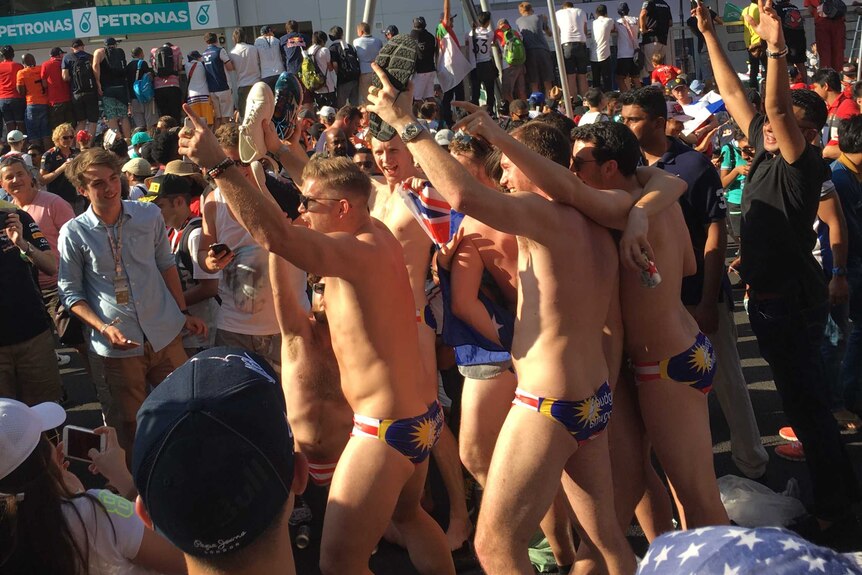 Men in Malaysian flag-printed swimming briefs dance in a crowd