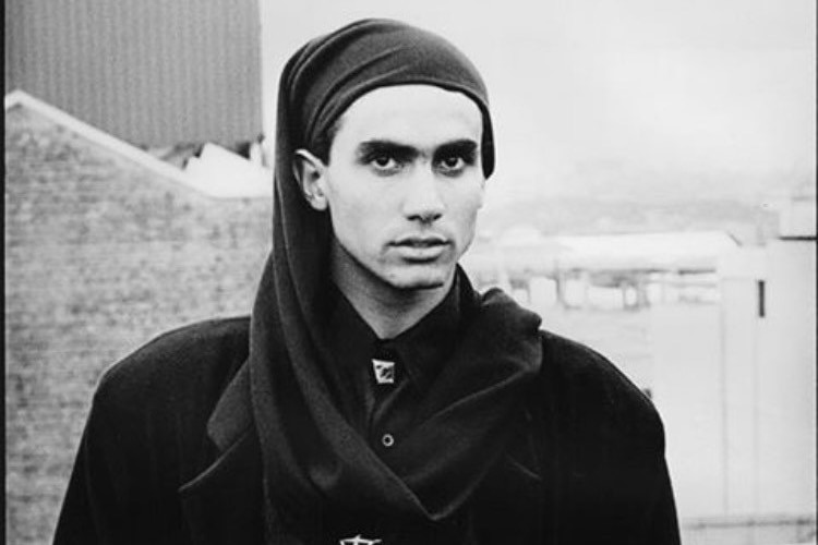 A black-and-white image of a young man wearing a hardscarf and modelling.