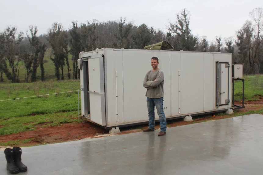 a man stands on a wet concrete slab beside a shipping container