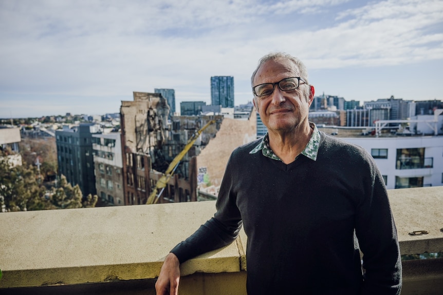 Man leaning on building with city in the background