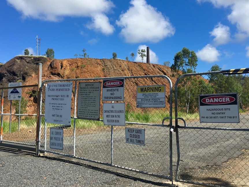 Fenced off red dirt area with lots of warning signs