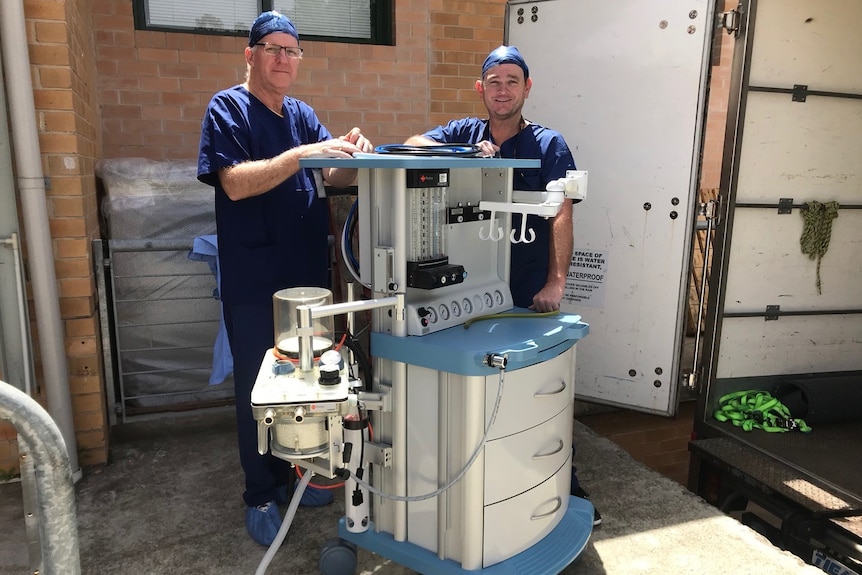 Two men standing with some medical equipment.