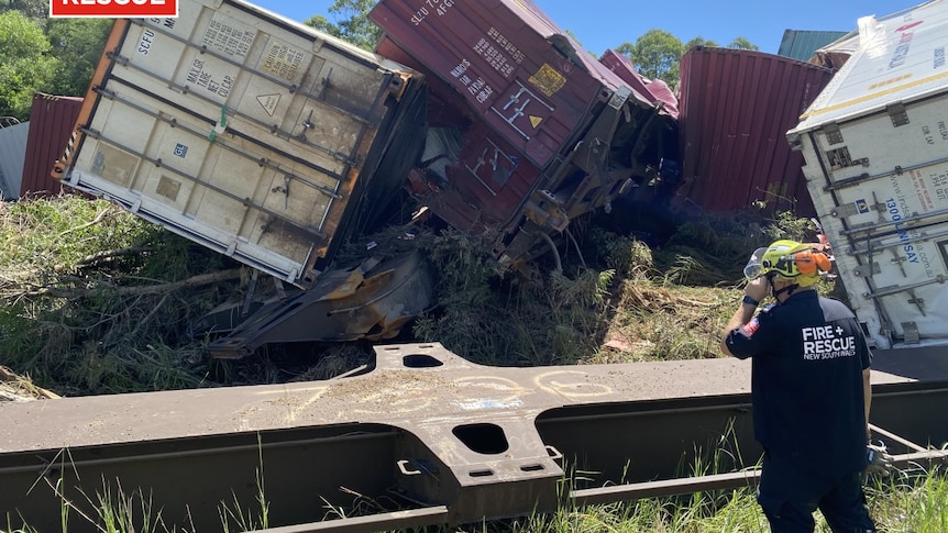 A Fire and Rescue officer looks at the derailed wagons of a freight train at Nana Glen.