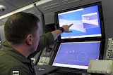 A US Navy crewman aboard a surveillance aircraft views a screen showing a reef in the disputed Spratly Islands, South China Sea