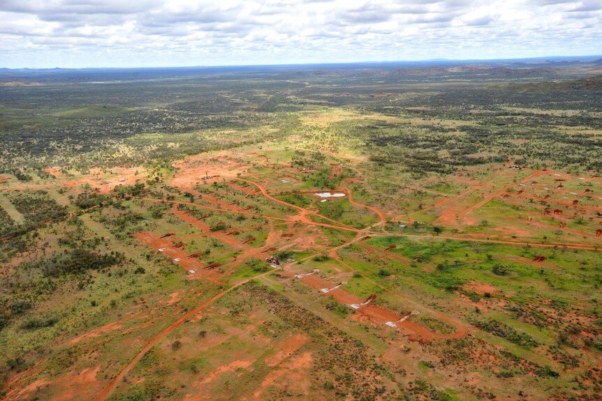An aerial view of red dirt and green scrubland in the Northern Territory.