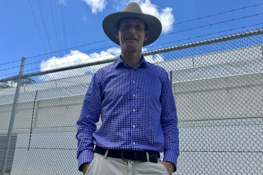 Medifarm director Adam Benjamin standing outside the fence. Big white building in the background.