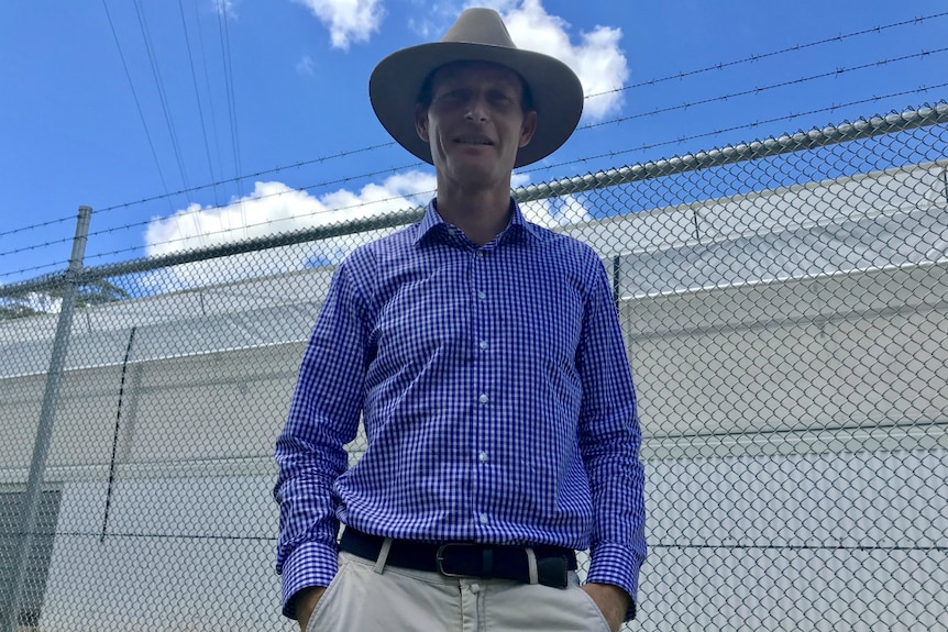 Medifarm director Adam Benjamin standing outside the fence. Big white building in the background.