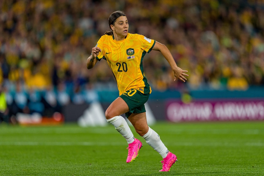 A soccer player wearing yellow and green and pink shoes runs during a game