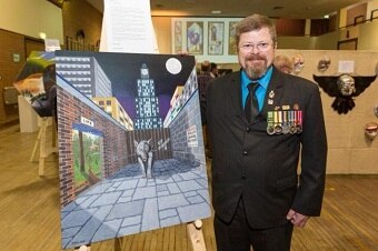 man in suit with medal standing next to painting