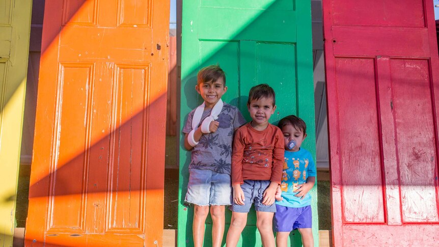 Three boys from Lulla's pose in front of brightly coloured doors.