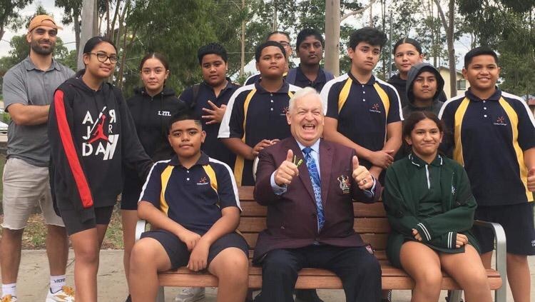 A group of mainly pacific Islander youth with an older white male giving a thumbs up, in a park