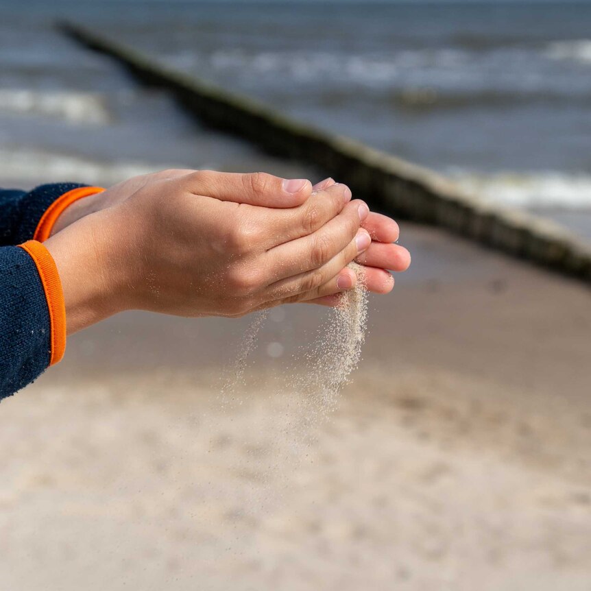 Close up of a woman's hands pouring sand at the beach
