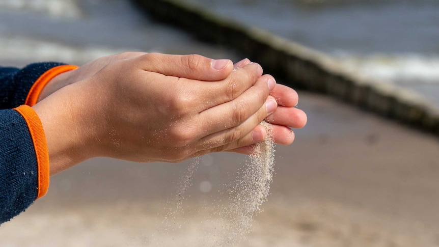 Close up of a woman's hands pouring sand at the beach