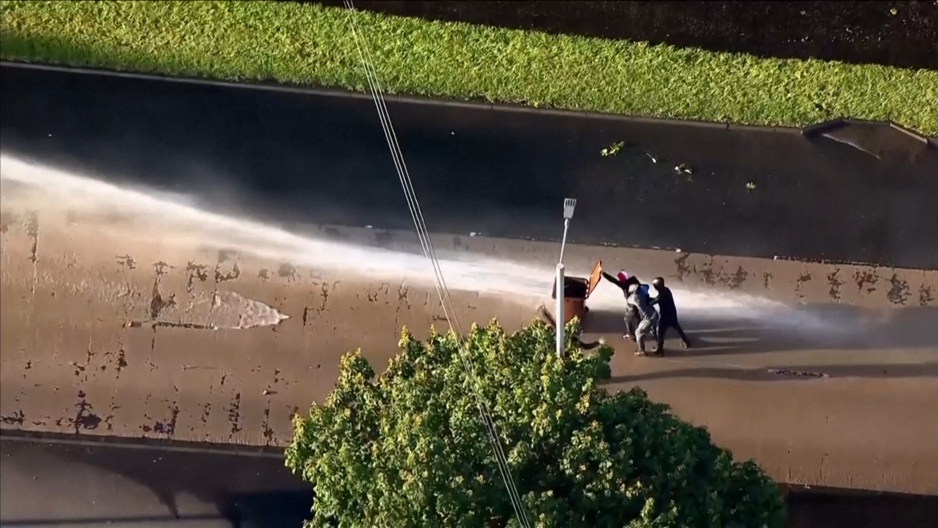 Protesters blocking water cannons with bin. 