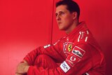 Michael Schumacher sits in his Ferrari kit in front of a red wall