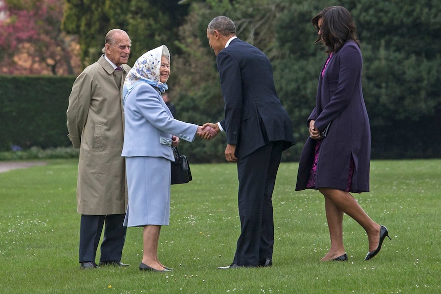Queen Elizabeth shakes hands with Barack Obama in a grass garden