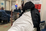 A man on a stretcher in a hospital room with his face obscured