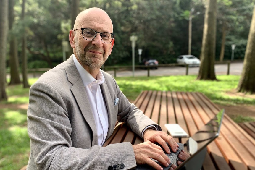 A man at a bench wearing a suit using a tablet with a keyboard