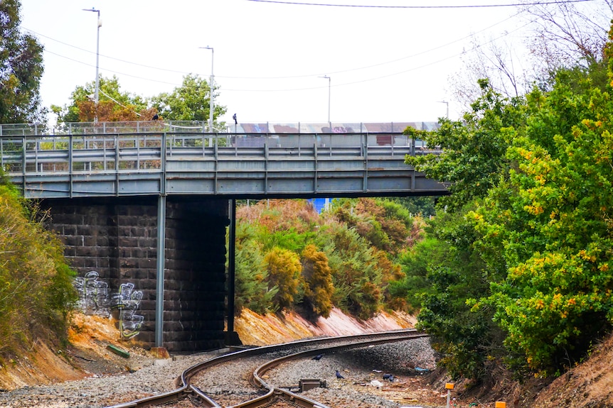 railway lines run beneath a bluestone bridge