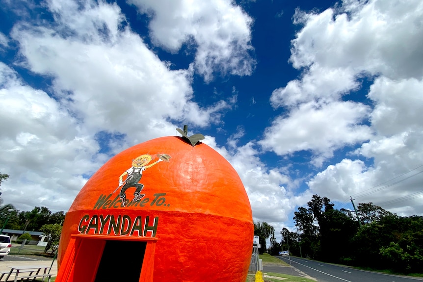 A large orange tourist roadside attraction with blue sky above it.