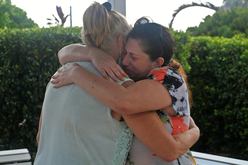 two women embrace outside an airport 