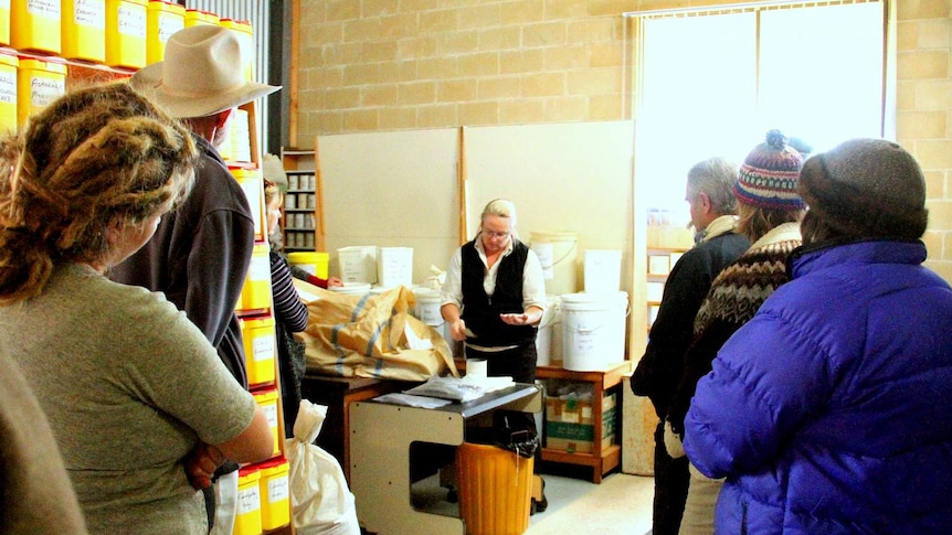 A group of Seed Savers visit a seed store, where the owner is showing them their range of seeds for sale.