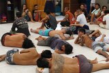 Men, many with tattoos on their arms, legs and backs, lie on the ground inside the Kerobokan prison.