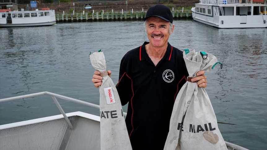 A man holding mail bags on a boat.