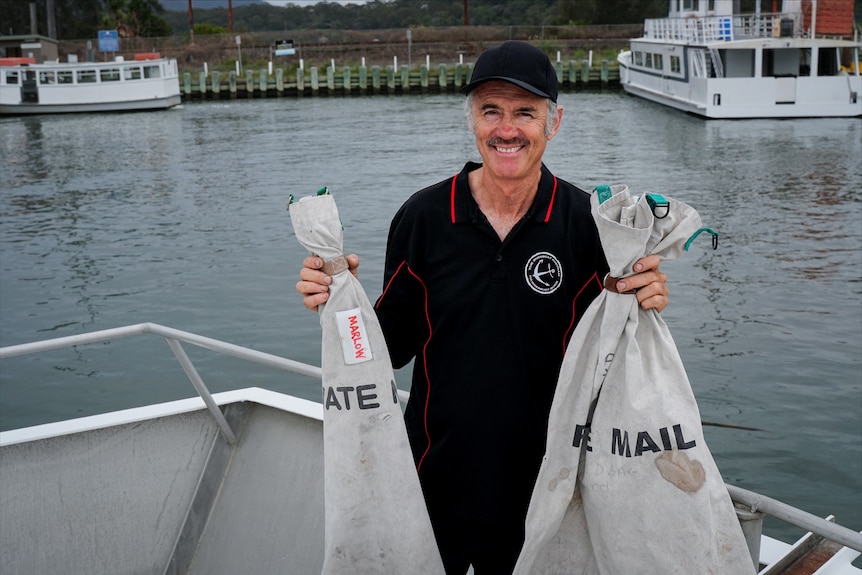 A man holding mail bags on a boat.